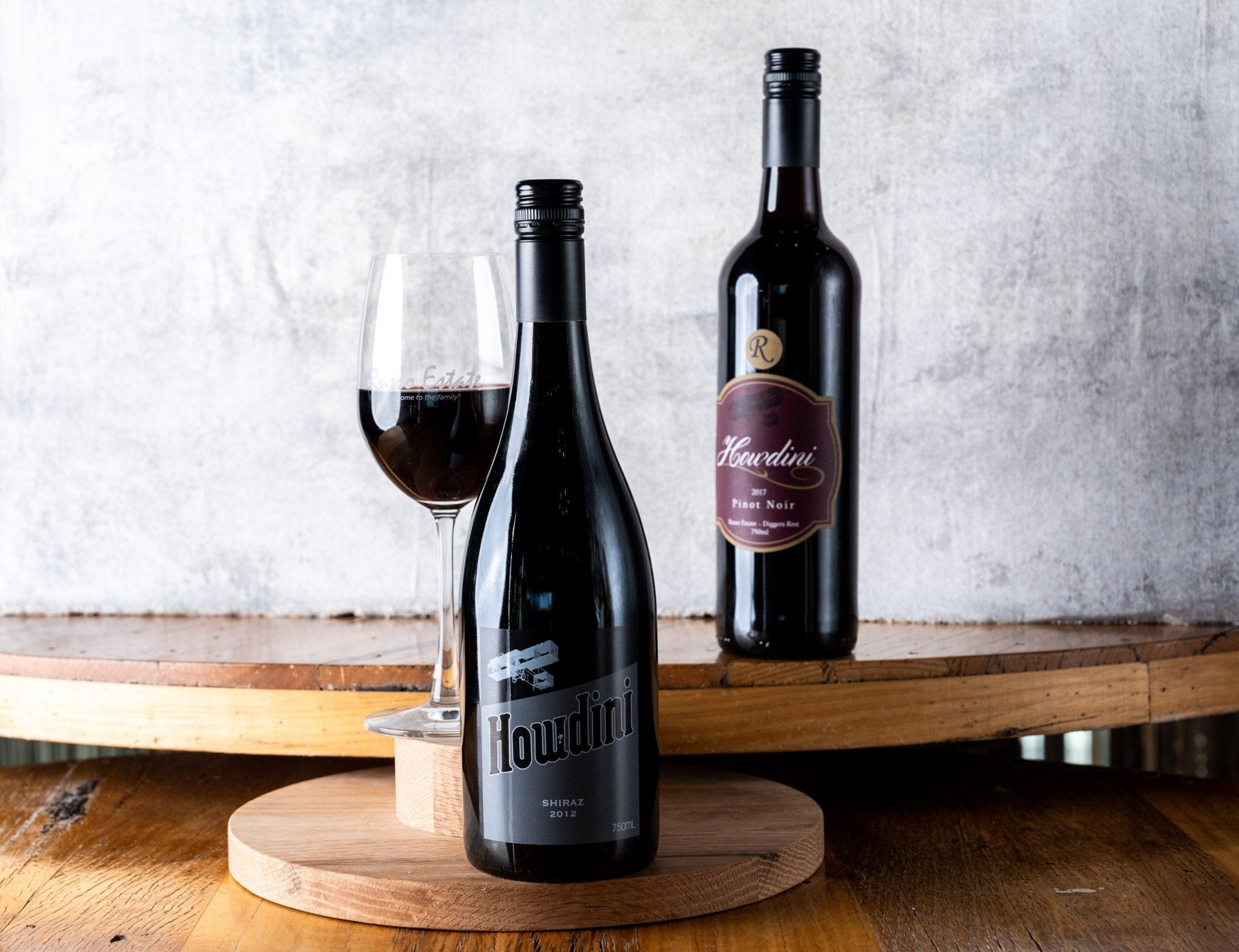 two bottle of wine of a table, glass of red wine, front facing